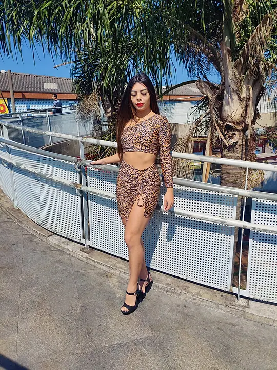 Modelo com cropped e saia de estampa de onça numa passarela ao ar livre